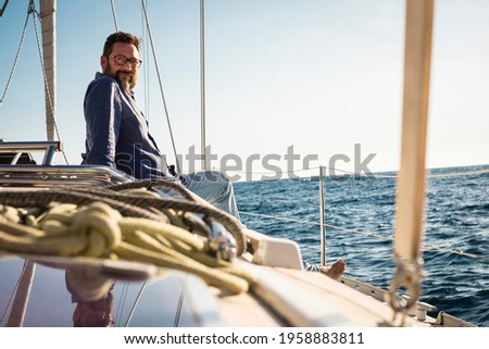 Adult man sit down on the sail boat deck enjoying the trip - travel lifestyle people on yacht - luxury life or tourist excursion concept - blue sea and sky with horizon in background