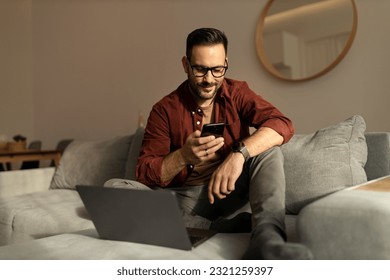 An adult man sitting on the sofa, using a mobile phone, being at home. - Powered by Shutterstock - Get 15% off with code: PIKWIZARD15