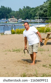 Adult Man Throwing Horseshoe Game Beach Activity QC Canada