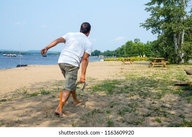 Adult Man Throwing Horseshoe Game Beach Activity QC Canada