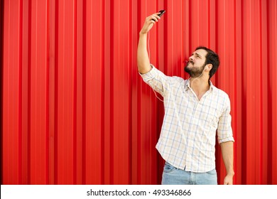 Adult Man Trying To Catch Signal To His Cellphone Holding Up In The Air His Phone On Red Background