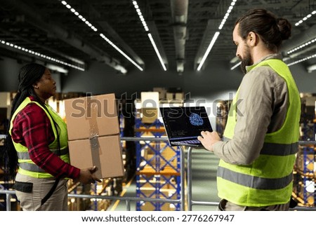 Adult man using AI-powered software with machine learning on laptop, artificial intelligence and neural networks supporting e-commerce operations, order fulfillment in large supply chain facility.