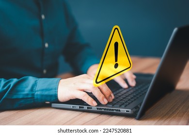 Adult man using computer laptop with triangle caution warning sign for notification error. Computer virus detected, personal data protection, network security and maintenance concept.
