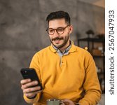 adult man wear eyeglasses and have fun while use cellphone and drink coffee at home