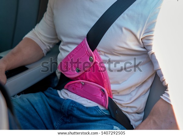 adult man wearing child seat belt in the car in the\
back seat