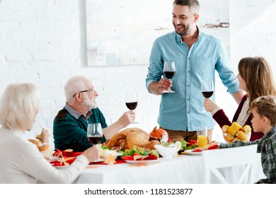 Adult Man With Wine Glass Making Toast While His Family Having Holiday Dinner On Thanksgiving 