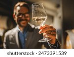 Adult man winemaker hold glass of white wine in winery