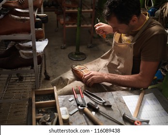 adult man working in a shoe factory, sewing the soles of the shoes manually - Powered by Shutterstock