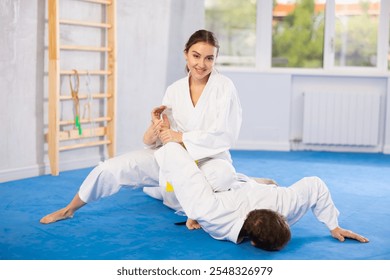 Adult man and young woman judokas practicing judo fighting in studio - Powered by Shutterstock