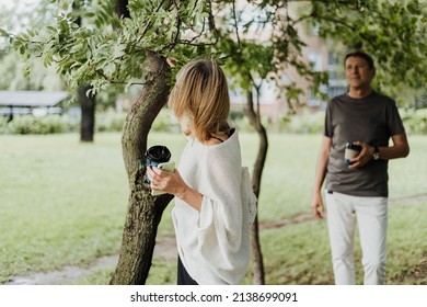 An Adult Mature Happy Couple In Love Hugging Outdoors In City Park. A Blonde Caucasian Man And Woman Spend Time Together And Drinking Coffee. Senior Wife And Husband Walking Outside