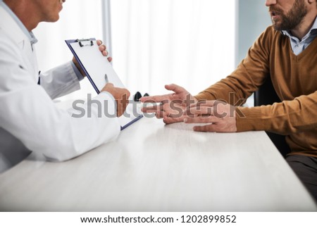 Adult medical adviser talking adout possible treatments and showing questionnaire for male patient Stock photo © 