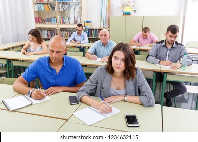 Adult Men And Women Take A Written Exam In The Classroom
