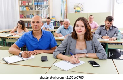 Adult Men And Women Take A Written Exam In The Classroom.