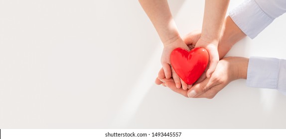 An adult, mother and child hold a red heart in their hands. Concept for charity, health insurance, love, international cardiology day. - Shutterstock ID 1493445557