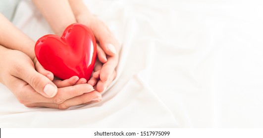 An Adult, Mother And Child Hold A Red Heart In Their Hands. Concept For Charity, Health Insurance, Love, International Cardiology Day.