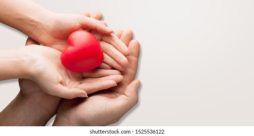 An Adult, Mother And Child Hold A Red Heart In Their Hands. Concept For Charity, Health Insurance, Love, International Cardiology Day.