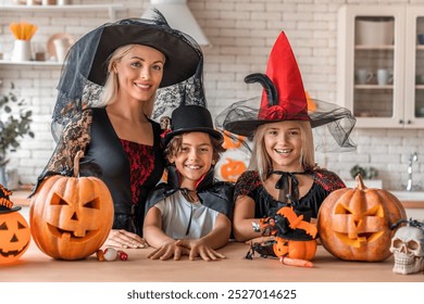 Adult mother and children standing in witch vampire costumes at the kitchen and looking in camera. Festive Halloween celebration with costumed family and pumpkin decorations in cozy kitchen - Powered by Shutterstock