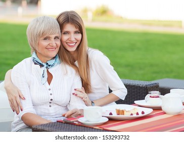 Adult Mother And Daughter Drinking Tea Or Coffee And Talking Outdoors 