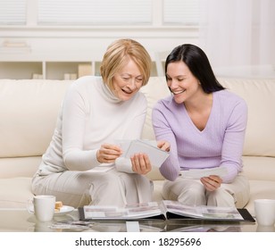 Adult Mother And Daughter Enjoying Photo Album In Livingroom