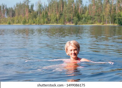 Adult Old Senior Woman Swimming In The Lake, Smiling. Healthy Lifestyle. Happy Retirement Concept. Mature Female In The Water In The Forest, Tempered, Hardening