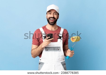 Adult painter man over isolated blue background surprised and sending a message