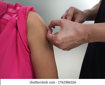 An Adult Patient Is Having A Subcutaneous Injection In The Deltoid. The Specialist Hands Giving The Injection Is Inserting The Needle Upwards Into The Deltoid,