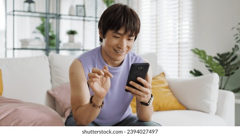 Adult people asia single LGBT gay man sitting at home sofa looking at dating game tinder app on mobile phone. Relax smile choose lover enjoy playing right swipe to find love couple match flirt chat. - Powered by Shutterstock