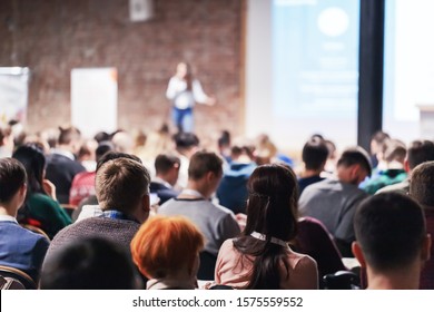 Adult people at conference listen to woman speaker providing lecture on scene in big conference hall. Business and Entrepreneurship concept. Audience at the conference hall. - Shutterstock ID 1575559552