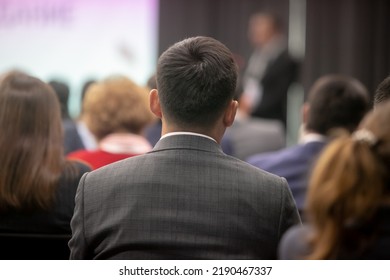 Adult People At Conference Listen To Woman Speaker Providing Lecture On Scene In Big Conference Hall. Business And Entrepreneurship Concept. Audience At The Conference Hall.