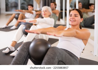 Adult people different ages practicing pilates with ball at group class in yoga studio - Powered by Shutterstock