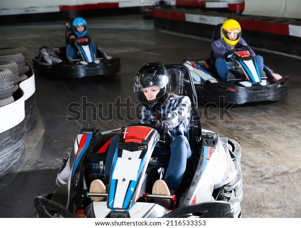 Adult people in helmets driving cars for karting\
in sport club indoor