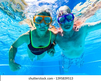 Adult people senior couple have fun swimmin in the pool underwater with coloured funny diving masks - dive concept and active retired man and woman enjoying the lifestyle - blue water caucasian adults - Powered by Shutterstock