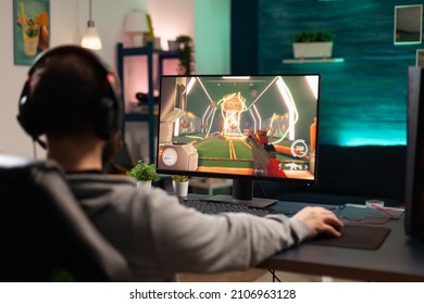 Adult playing video games on monitor with mouse and headphones. Gamer using mousepad and headset to play online games on computer. Player having fun with gaming and electronic game