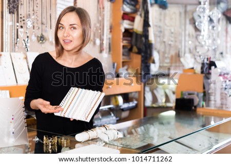 Adult seller offering the colored necklaces and pendants in the store 
