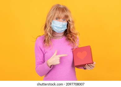 adult or senior woman with face mask isolated on background with gift box with heart - Powered by Shutterstock