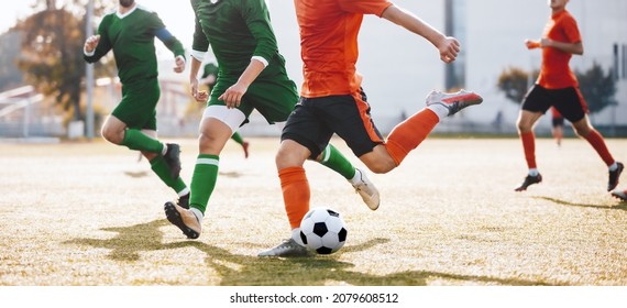 Adult Soccer Players Running After Ball and Kicking League Match. Group of Footballers in a Duel. Soccer Players in Orange and Green Jersey T-shirts