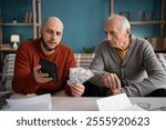 an adult son helping his elderly father calculate the budget and prepare documents for paying utility bills. Copy space