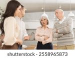 Adult son introducing girlfriend to senior parents standing with crossed arms and expression of skepticism and disapproval in cozy home kitchen ..