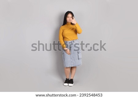 The adult Southeast Asian woman standing on the grey background.