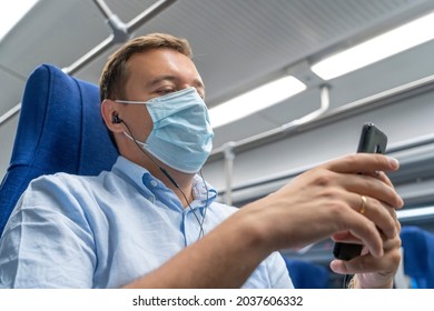 Adult Student Learning With Online Course In Smart Phone In Train. Handsome Man With Medical Mask Listening Music On Mobile Phone While Traveling By Train