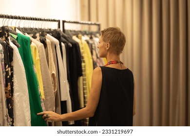 Adult stylish woman fashion consultant looking over the clothes at the boutique - Powered by Shutterstock