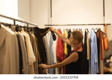 Adult stylish woman fashion consultant looking over the clothes at the boutique - Powered by Shutterstock