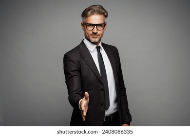 Adult successful employee business man corporate lawyer wear classic formal black suit shirt tie work in office stretch hands for handshake gesture isolated on plain grey background studio portrait - Powered by Shutterstock