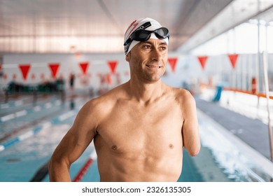 An adult swimmer with an amputated arm is happily posing in a heated indoor pool. Concept of people with disabilities, athletes with an amputated arm, swimming for the disabled. - Powered by Shutterstock