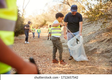 Adult Team Leader With Group Of Children At Outdoor Activity Camp Collecting Litter Together - Powered by Shutterstock