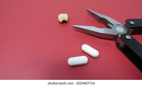 Adult Tooth set on Red Surface with Plyers and Pain Pills
