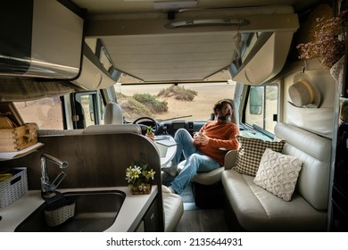 Adult traveler man sit down inside modern cozy mobile home camper van looking nature outside. Travel and vanlife lifestyle for alternative free people. Camper van interior and holiday vacation