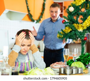 Adult Unhappy Couple Quarreling At Kitchen Decorated For Christmas Celebration