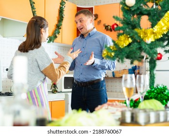 Adult Unhappy Couple Quarreling At Kitchen Decorated For Christmas Celebration