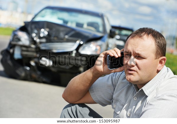Adult upset\
driver man discussing on mobile phone in front of automobile crash\
car collision accident in city\
road